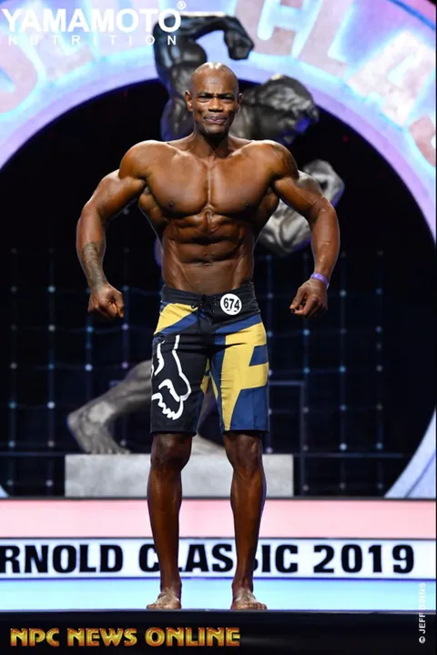 Antony Bessala en pose de face sur la scene de l'Arnold Classic 2019, short bleu et jaune
