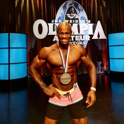 Antony Bessala avec une medaille devant le panneau Joe Weider's Olympia Amateur Las Vegas